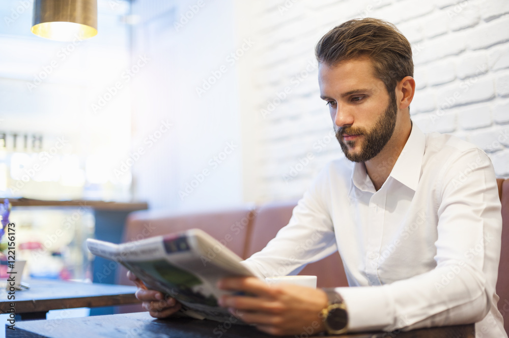 Businessman sitting in a cafe reading newspaper Businessman sitting in a cafe reading newspaper