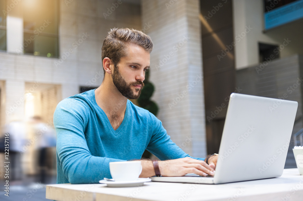 Young man sitting at table using laptop Young man sitting at table using laptop