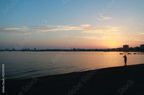 Fototapeta Naklejka Na Ścianę i Meble -  Man walking on the beach at sunset