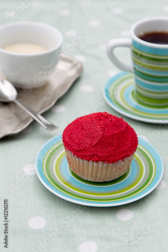 Home made red cupcake on a green plate with coffee and cream