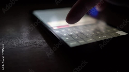 Man checking facebook via smartphone display touchscreen at night. photo
