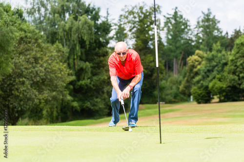 Senior golf player aiming his stroke to the hole