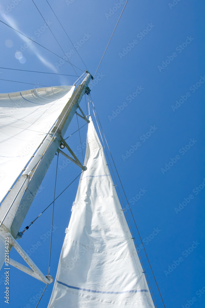 white yacht sails against the blue sky of tropical