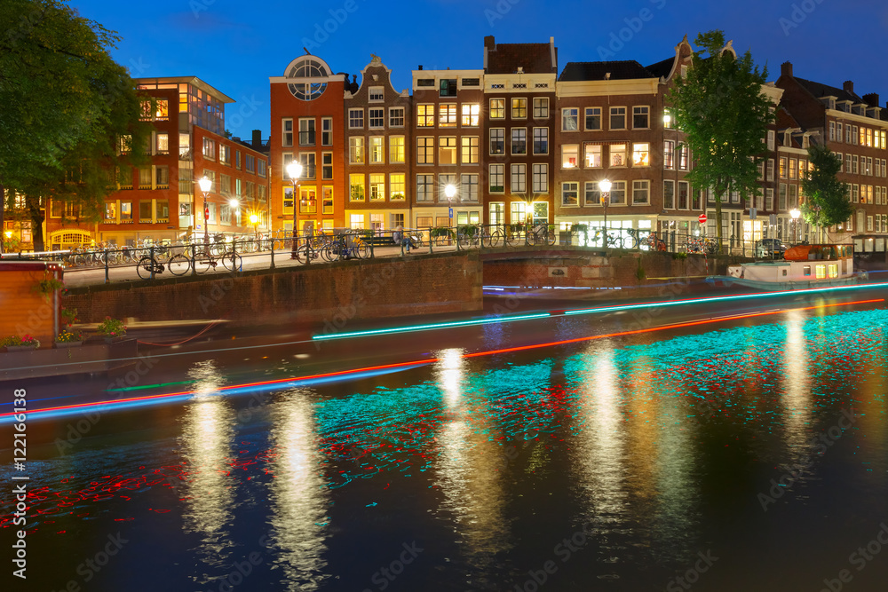 Amsterdam canal Prinsengracht with typical dutch houses, bridge and luminous track from the boat at night, Holland, Netherlands.
