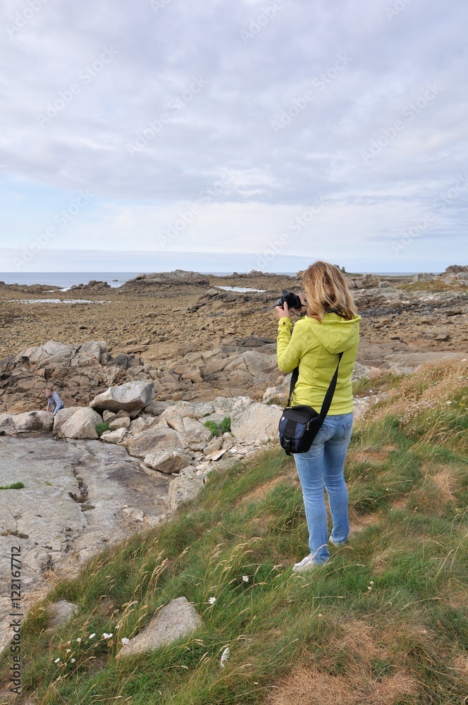 Une randonneuse prend une photo du bord de mer en Bretagne
