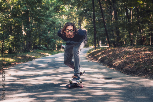 Skateboarder ride a longboard skateboard on the road through the forest. Freeride longboard skating photo