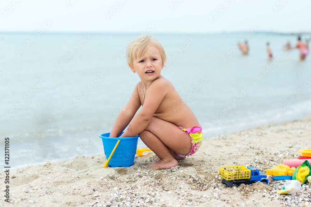 Adorable toddler girl playing with beach toys on white sand beach Adorable toddler girl playing with beach toys on white sand beach