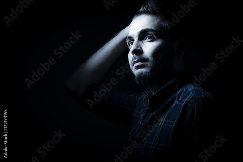 Boy in darkness isolated inside Studio