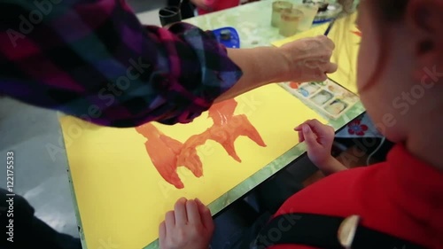 The girl draws a picture paints in classroom photo