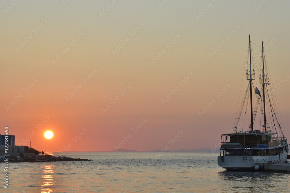 Sunset in Postira harbor on Brac Island in Croatia with a boat in foreground. Sunset in Postira harbor on Brac Island in Croatia with a boat in foreground.