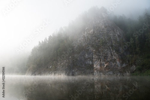 Rocky mountain in the morning fog with reflection in the river © ilyaska