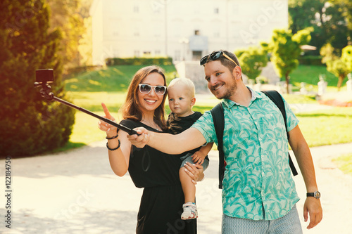Photography Young family with toddler child making selfie photo on motion camera in park of