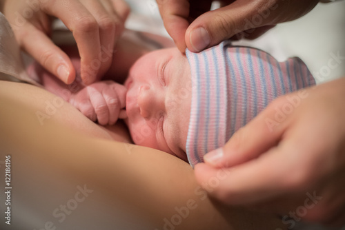 Fotografie, Obraz New born boy on mom's chest. Dad adjusting hat.