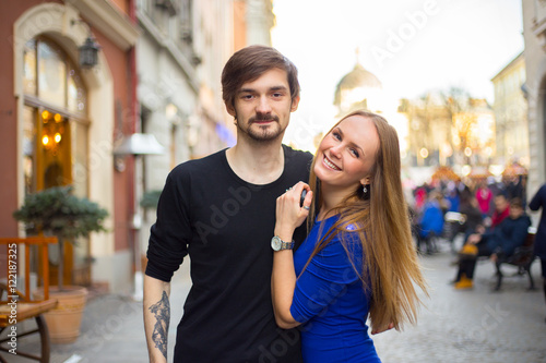 Young caucasian cheerful couple hugging at the european city wit