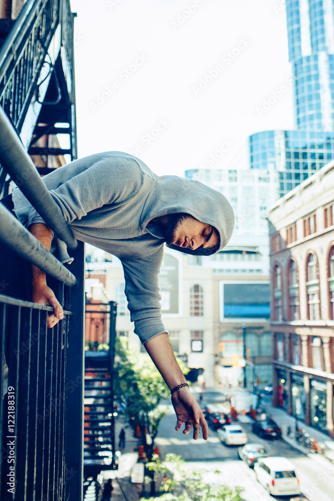 Conceptual art portrait of beautiful handsome pensive sad tired gothic young middle east brunette man with beard in hoodie, standing on staircase in city urban looking down on street Conceptual art portrait of beautiful handsome pensive sad tired gothic young middle east brunette man with beard in hoodie, standing on staircase in city urban looking down on street
