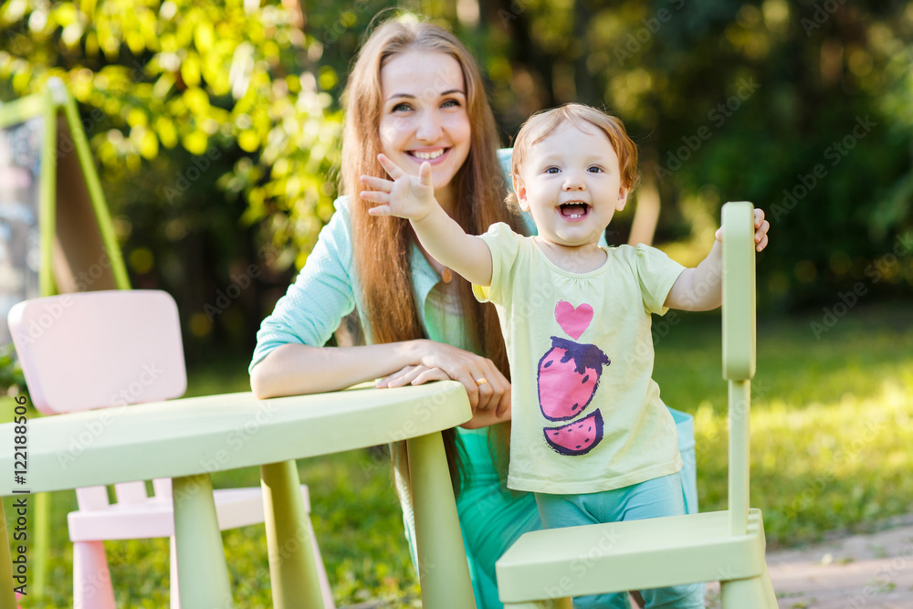 Fototapeta premium Mother with little daughter in park near children's furniture