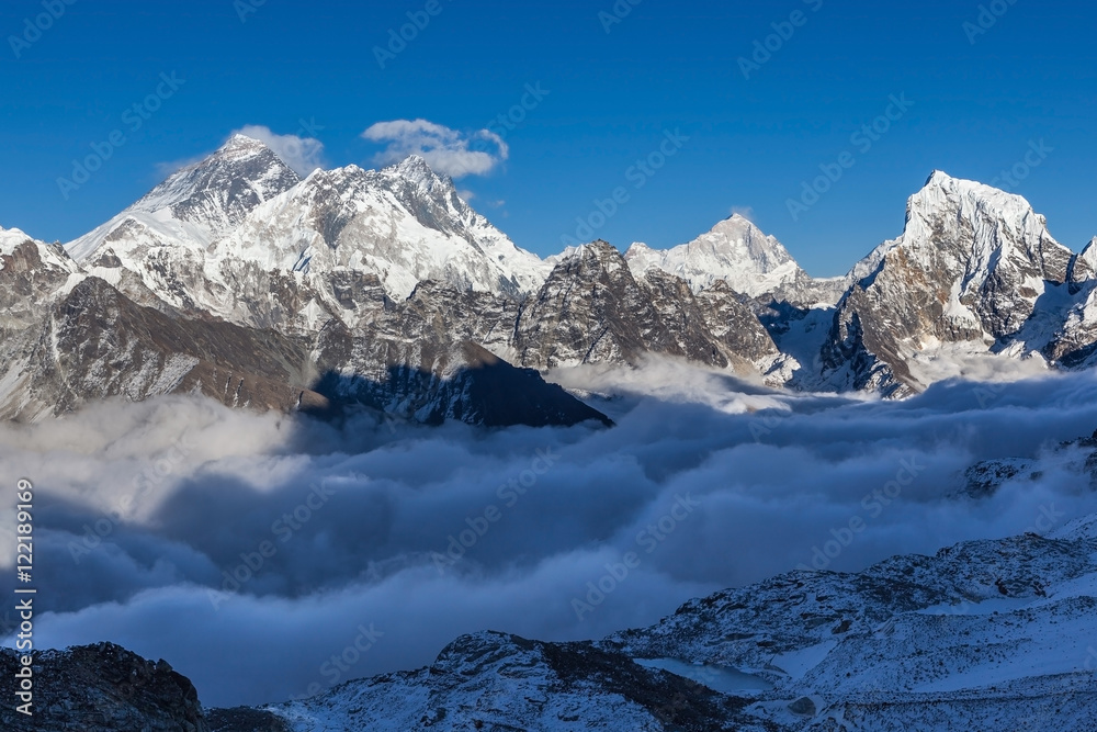 Mount Everest view from Renjo La pass. Amazing mountain valley filled with curly clouds. Dramatic snowy peak of Everest rise above river of clouds. Sagarmatha National Park, Nepal, Himalayas.