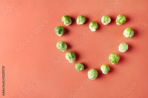 Brussels sprouts heart love shape on red background. Seasonal vegetables in modern style pattern