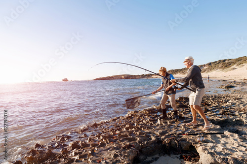 Senior man fishing with his grandson