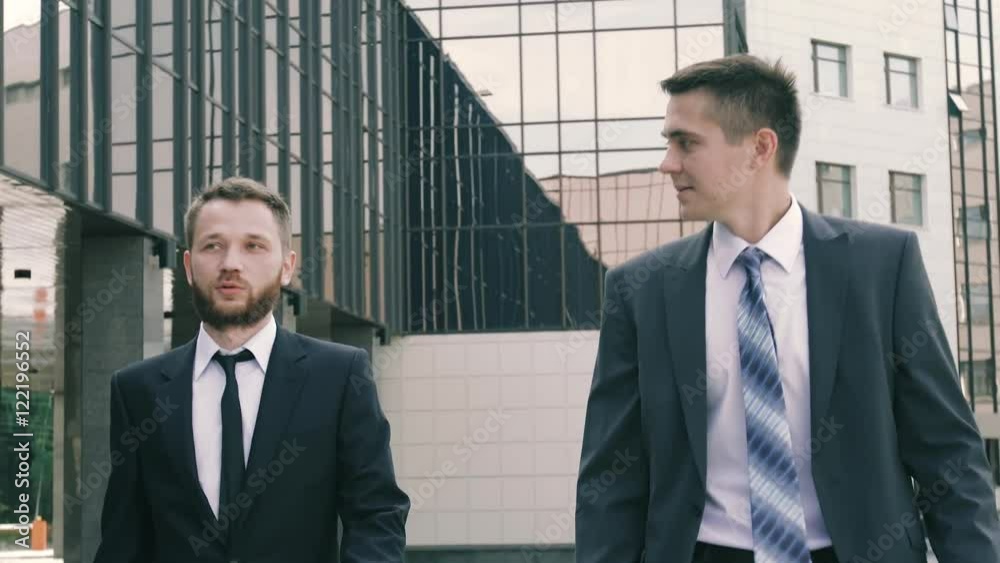 Close-up of young businessmen walking against the business center background