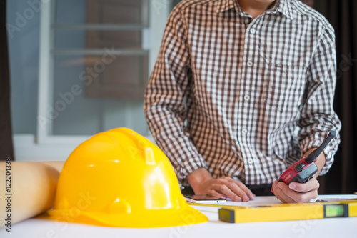  young male architect working on blueprints spread out on a table