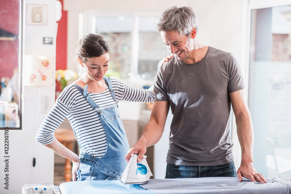 At home, man performs ironing to relieve his pregnant wife At home, man performs ironing to relieve his pregnant wife