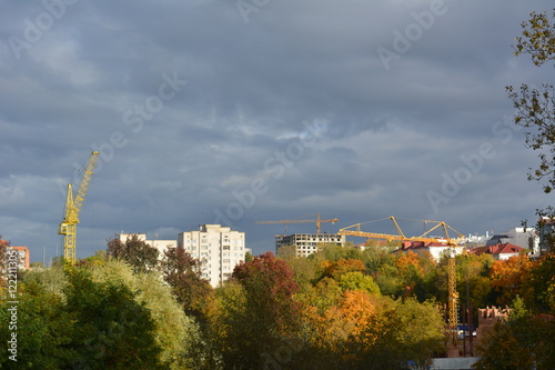 beautiful cityscape autumn landscape: colorful trees, crane, dark sky