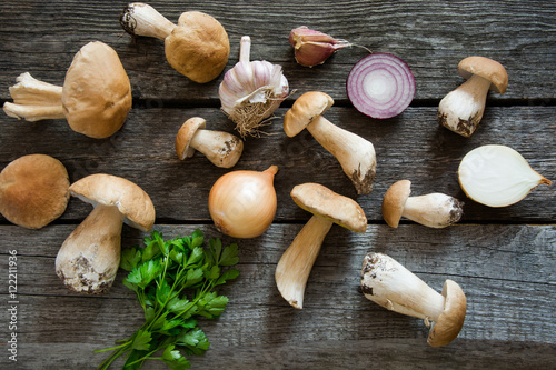 Fresh white mushrooms from forset on a rustic wooden board, overhead view.
