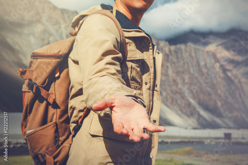 Young travel man lending a helping hand in outdoor mountain scenery. photo