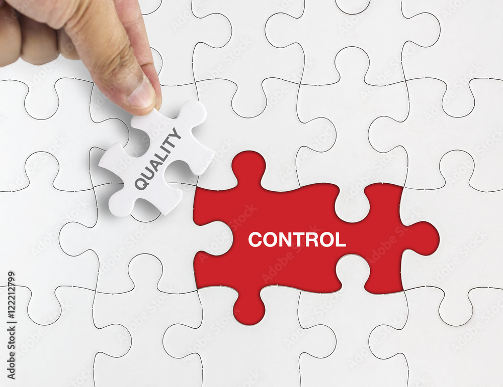 Hand holding piece of jigsaw puzzle with word QUALITY CONTROL Hand holding piece of jigsaw puzzle with word QUALITY CONTROL