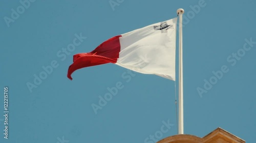 Flag of Malta in front of blue sky floating on flag pole. 4K footage. Real time shot. photo