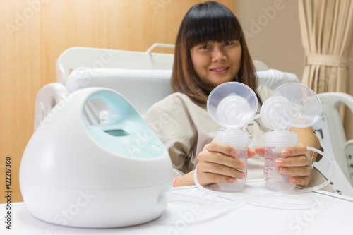 Beautiful asian mother holding breast pump.