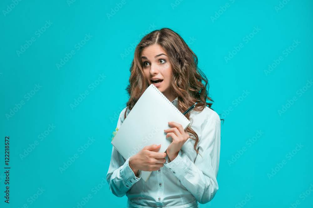 Surprised young business woman with pen and tablet for notes on blue background Surprised young business woman with pen and tablet for notes on blue background