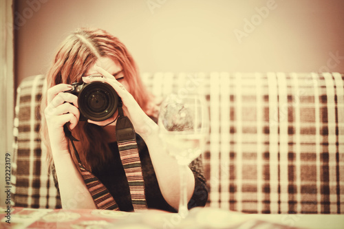 Woman with red hair hold camera take a photo at cafe