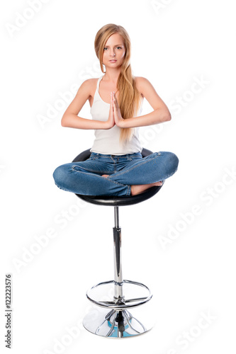 Vertical shot of a young beautiful long haired woman meditating seated on an office or bar chair isolated on white background. © Magryt