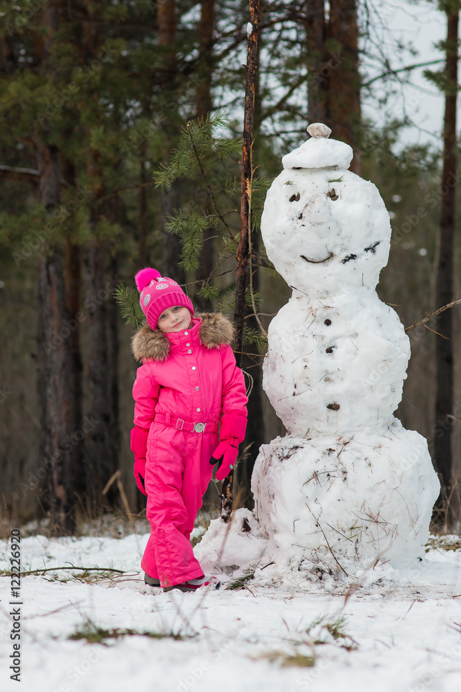 Girl next to a snowman winter day in the forest