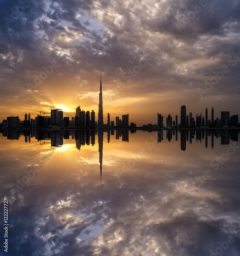 Fascinating reflection of tallest skyscrapers in Business Bay district during dramatic sunset. Downtown summer day. Construction built at evening time. Dubai, United Arab Emirates.