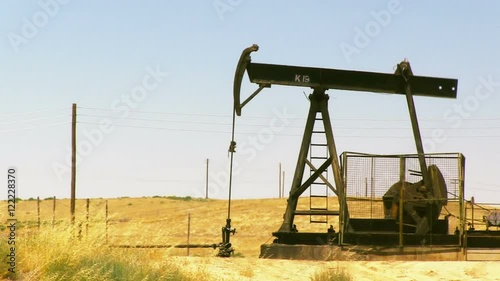 A stationary shot of an oil rig pumping oil in a field near Bakersfield, CA.