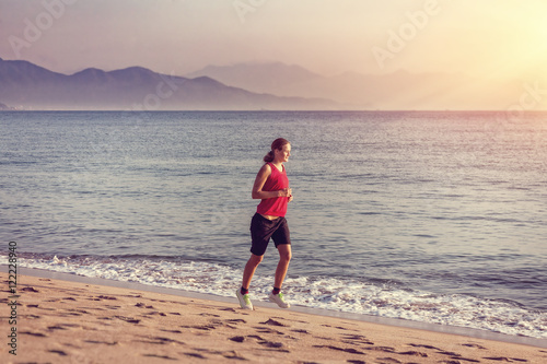 Girl running on the beach at sunrise