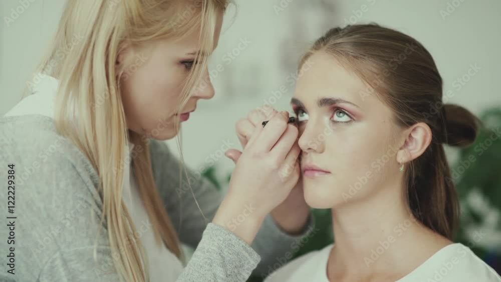 Make-up work. Make-up artist and model. Makeup. Girl makeup with long white hair. Makeup artist paints eyeliner lower eyelids model. Eye makeup. Eye Liner Make-up work. Make-up artist and model. Makeup. Girl makeup with long white hair. Makeup artist paints eyeliner lower eyelids model. Eye makeup. Eye Liner