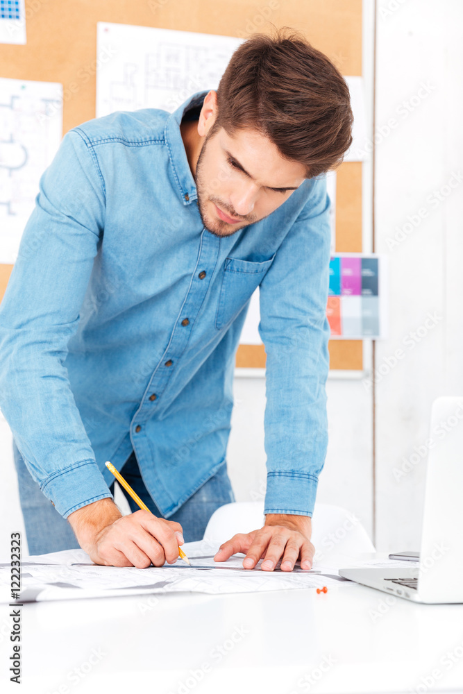 Fotografie Young businessman making notes while standing at the office desk