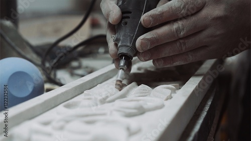 Engineer engraver working with tools on a marble ornament plate, close up