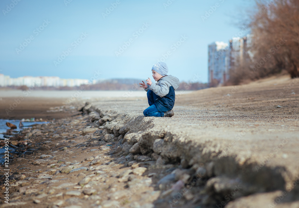 мальчик сидит на берегу реки
