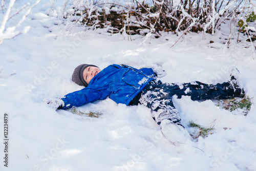мальчик лежит в снегу на спине