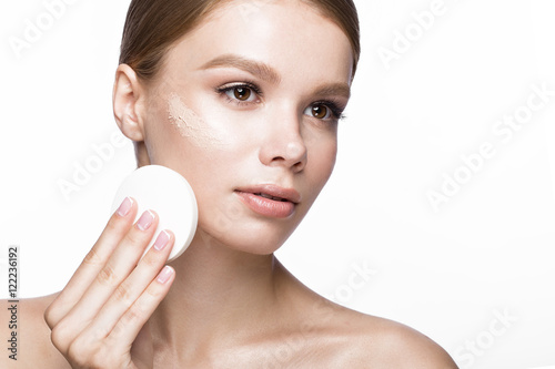 Beautiful young girl with sponge for application make-up and French manicure. Beauty face. Picture taken in the studio on a white background.