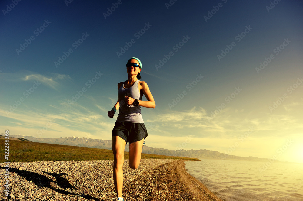 healthy young fitness woman trail runner running on sunrise seaside