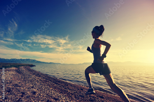 healthy young fitness woman trail runner running on sunrise seaside