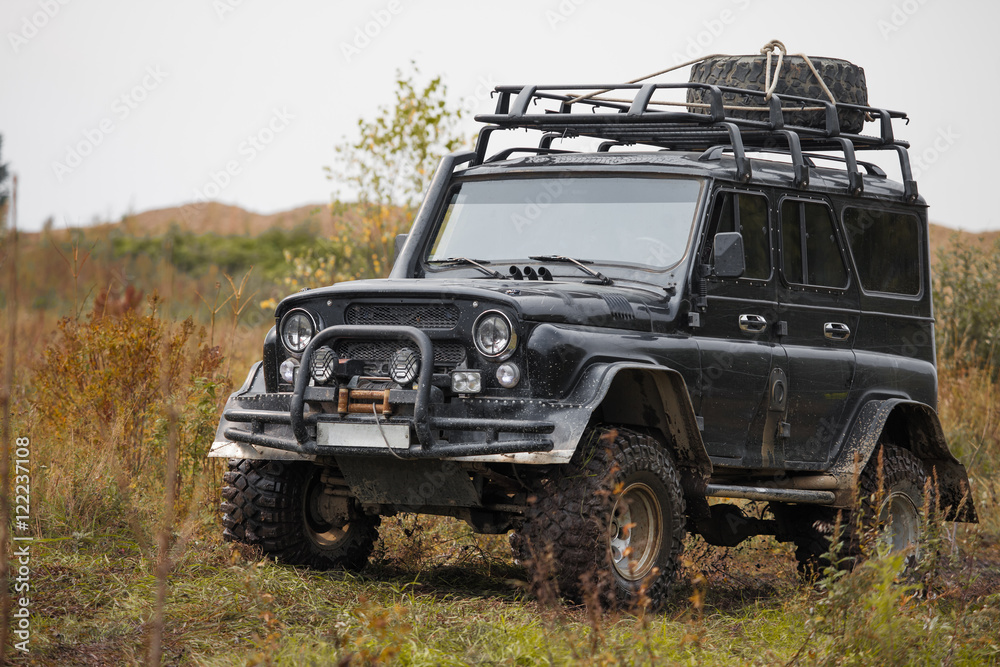 Fototapeta premium Russian black off road car UAZ in a meadow