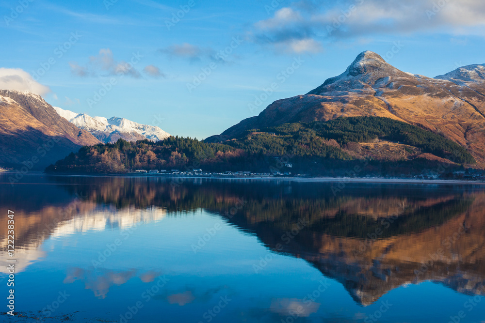 Mountains with mirror like reflections upon Loch in Scotland, UK