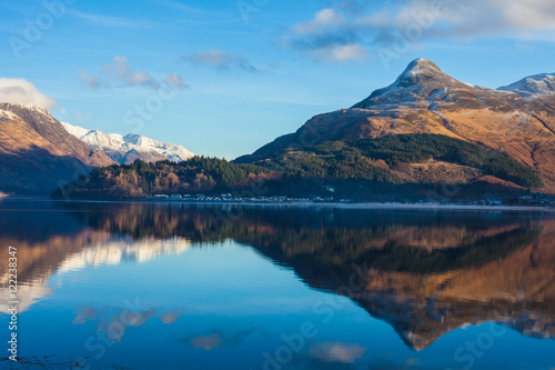 Mountains with mirror like reflections upon Loch in Scotland, UK